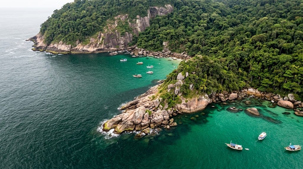 Vista aérea de una punta rocosa cubierta de selva con calas de agua turquesa y varias embarcaciones fondeadas